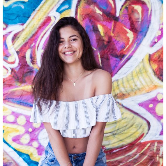 adolescente qui sourit devant un mur grafiti